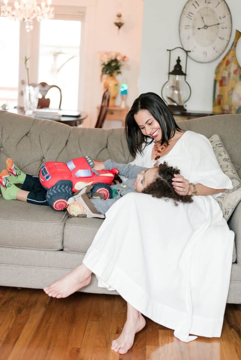 Vida DeOlivier: A stay-at-home mom entrepreneur sitting on the couch playing with her son.