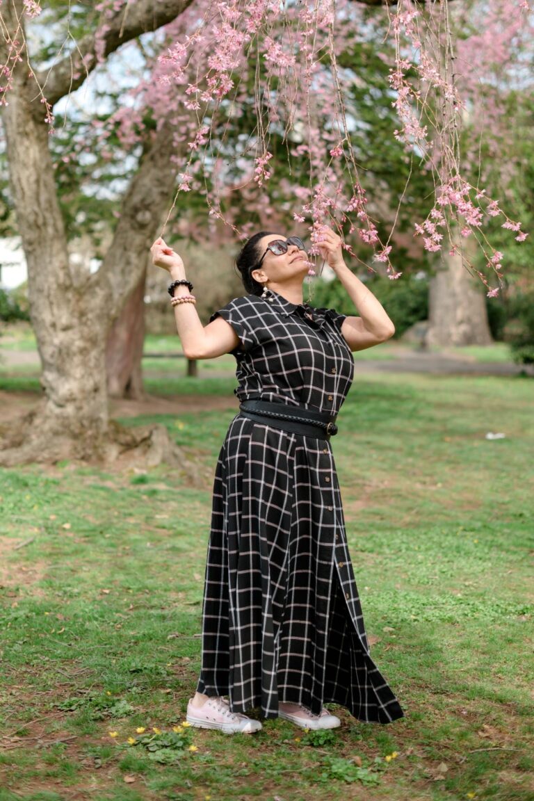 Vida DeOlivier at a park, smelling pink flowers-enjoying nature.